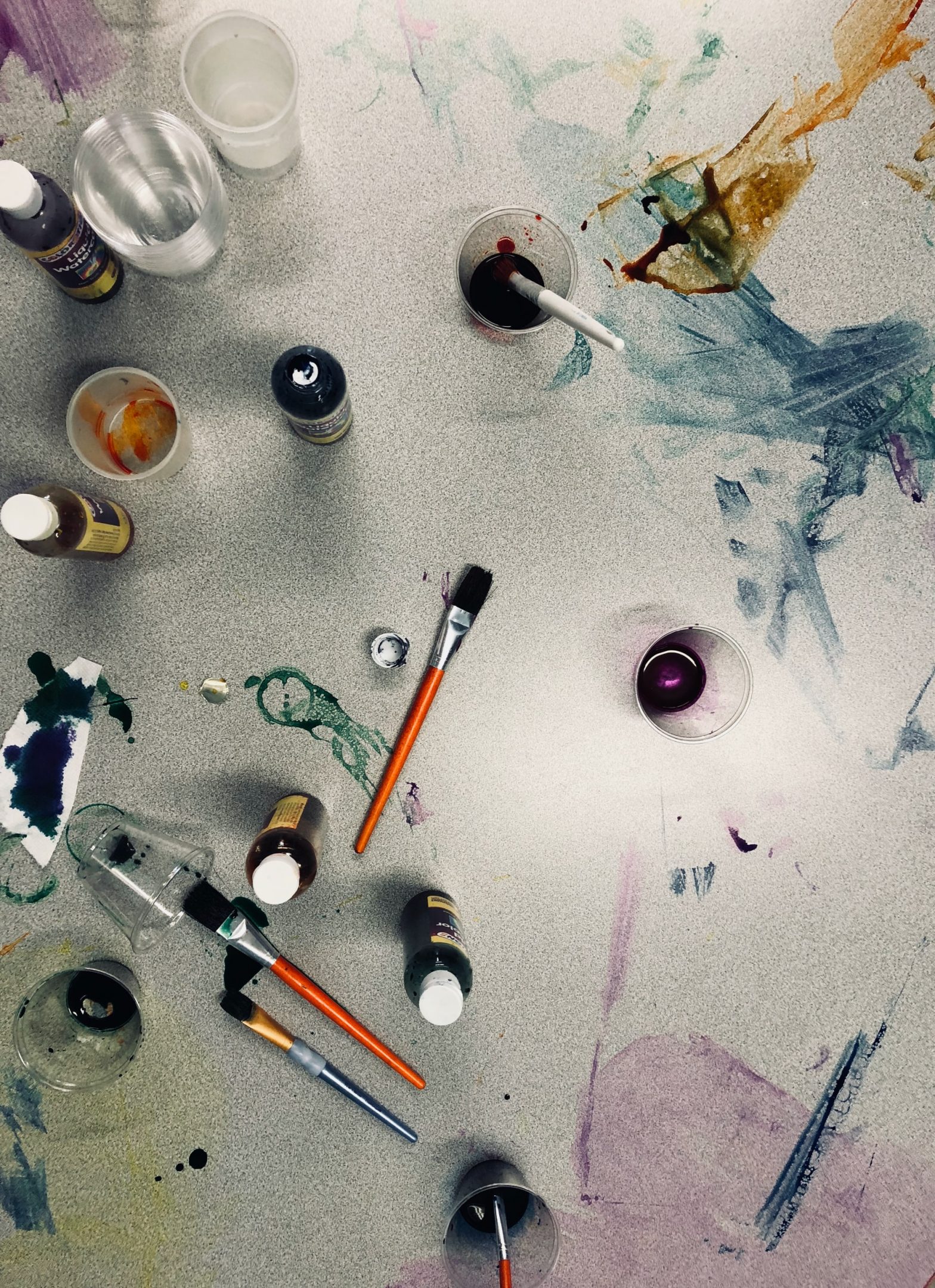 artist paints on a table by Sydney Rae Unsplash